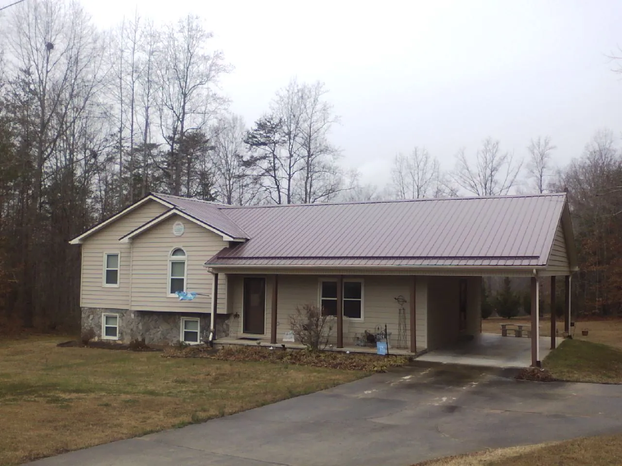 Burgundy metal roof on a tan split level home with an attached carport in Mc Lean