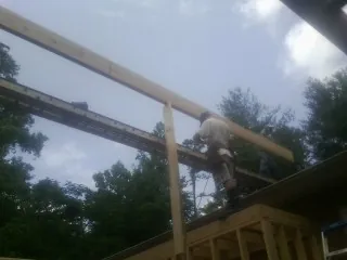 Carpenter setting a ridge beam over a new addition frame — Ice Dam Removal by Roofing Brothers in Mc Lean